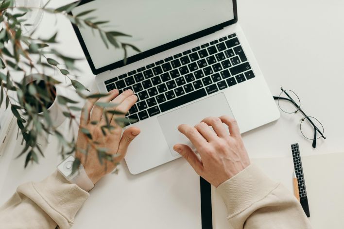 Person in Beige Long Sleeve Shirt Using Macbook Pro