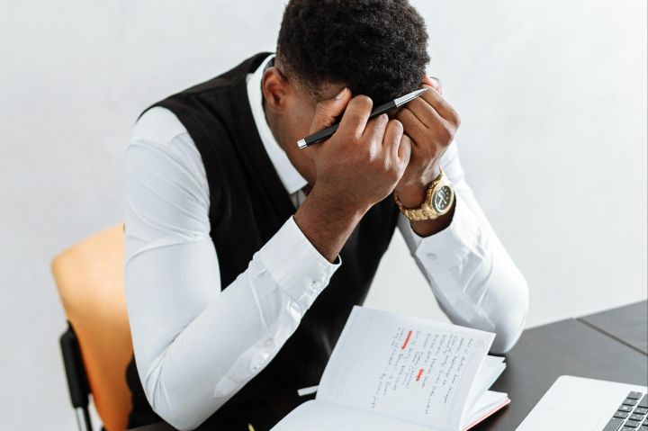 Man in White Dress Shirt Sitting on Chair in Front of Table With Macbook Pro