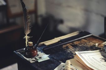 Feather pen on a wooden desk with old documents