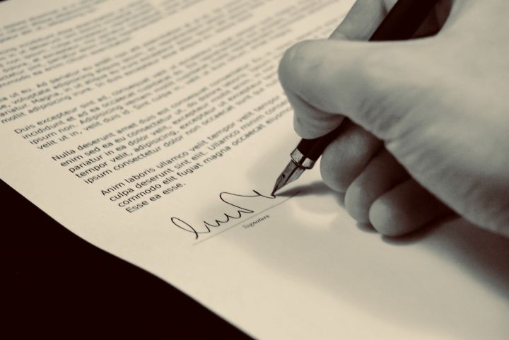 someone signing a document with an old fashion pen