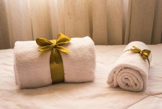 Luxurious white towels adorned with golden ribbons on a bed, creating an elegant and welcoming atmosphere.