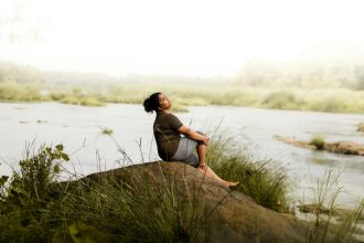 Woman enjoying a peaceful moment by the riverside, embracing nature's serenity.