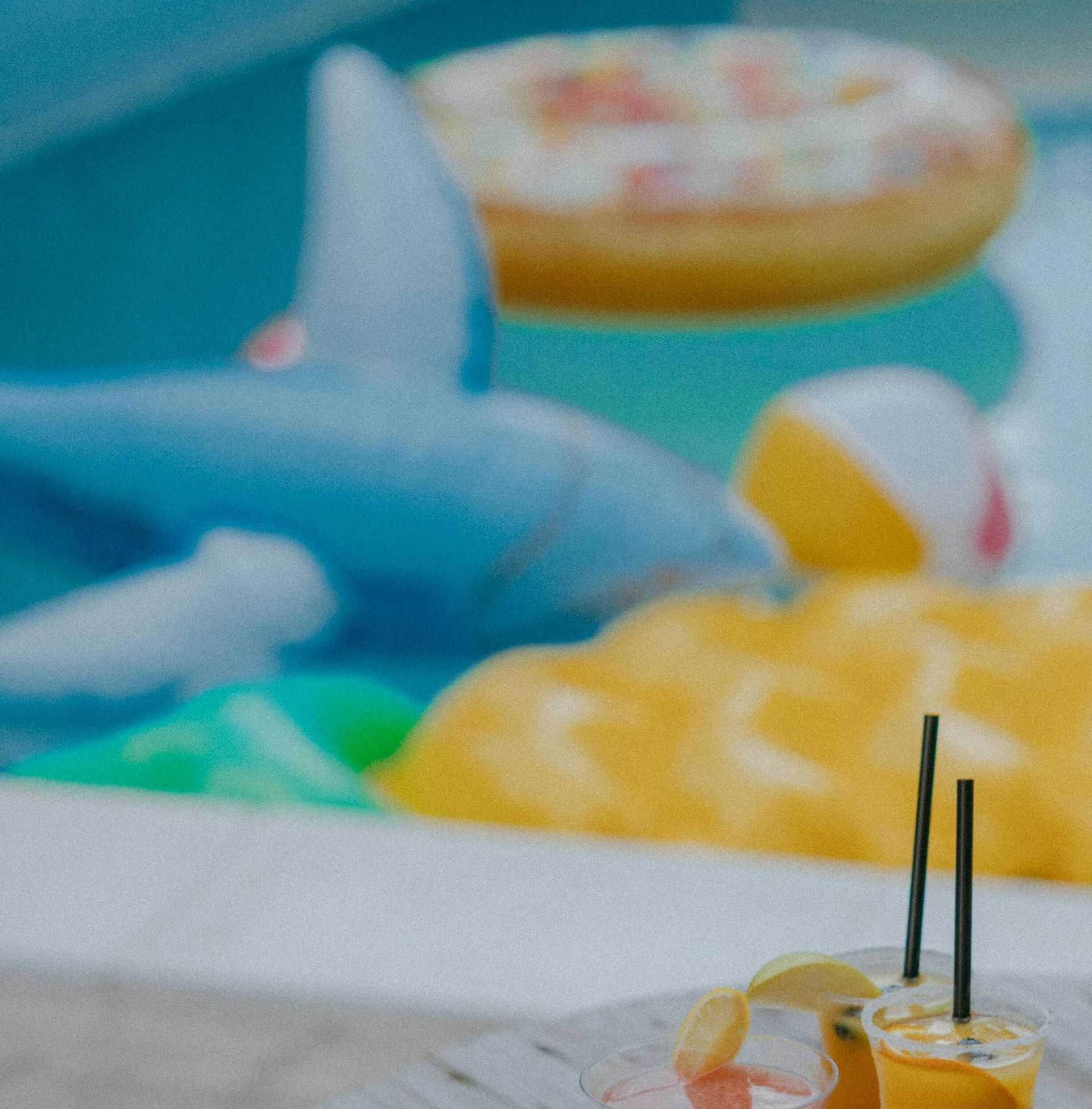 Colorful cocktails by the pool with fun inflatable shapes creating a tropical vibe.