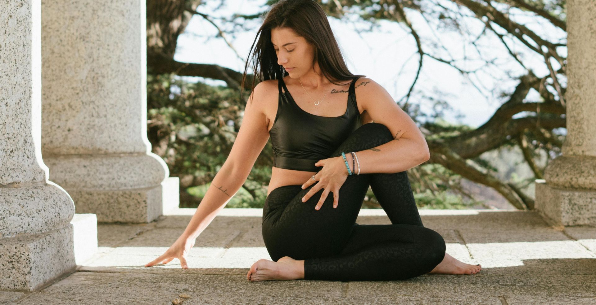 Woman practicing yoga outdoors, conveying tranquility and mindfulness amidst stone columns.