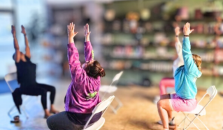 Group of adults practicing yoga outdoors in a park surrounded by trees.