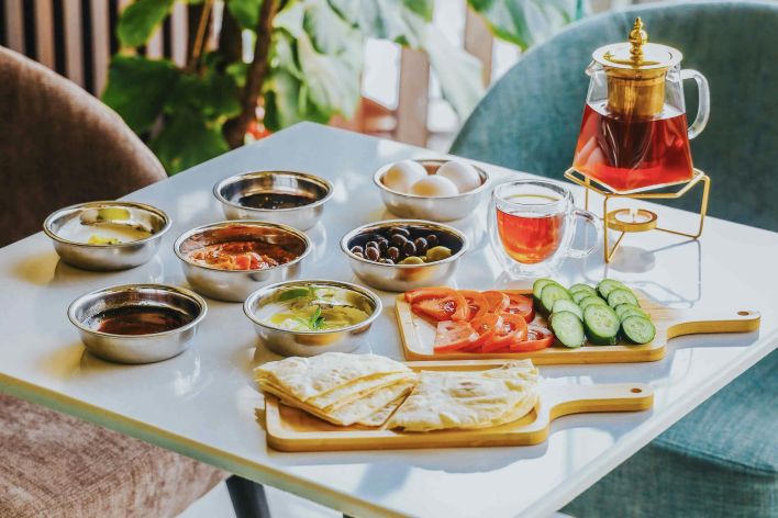 A vibrant spread of traditional Arabic breakfast with tea, fresh vegetables, and dips.