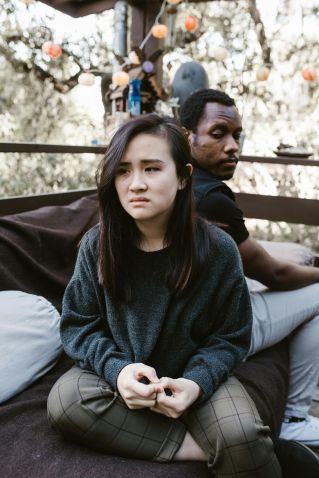 A couple sitting outdoors, showing signs of disagreement and emotional conflict.