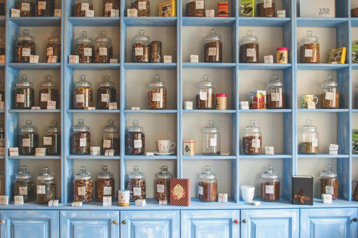 Organized display of herbal tea jars on vibrant blue shelves in a shop.
